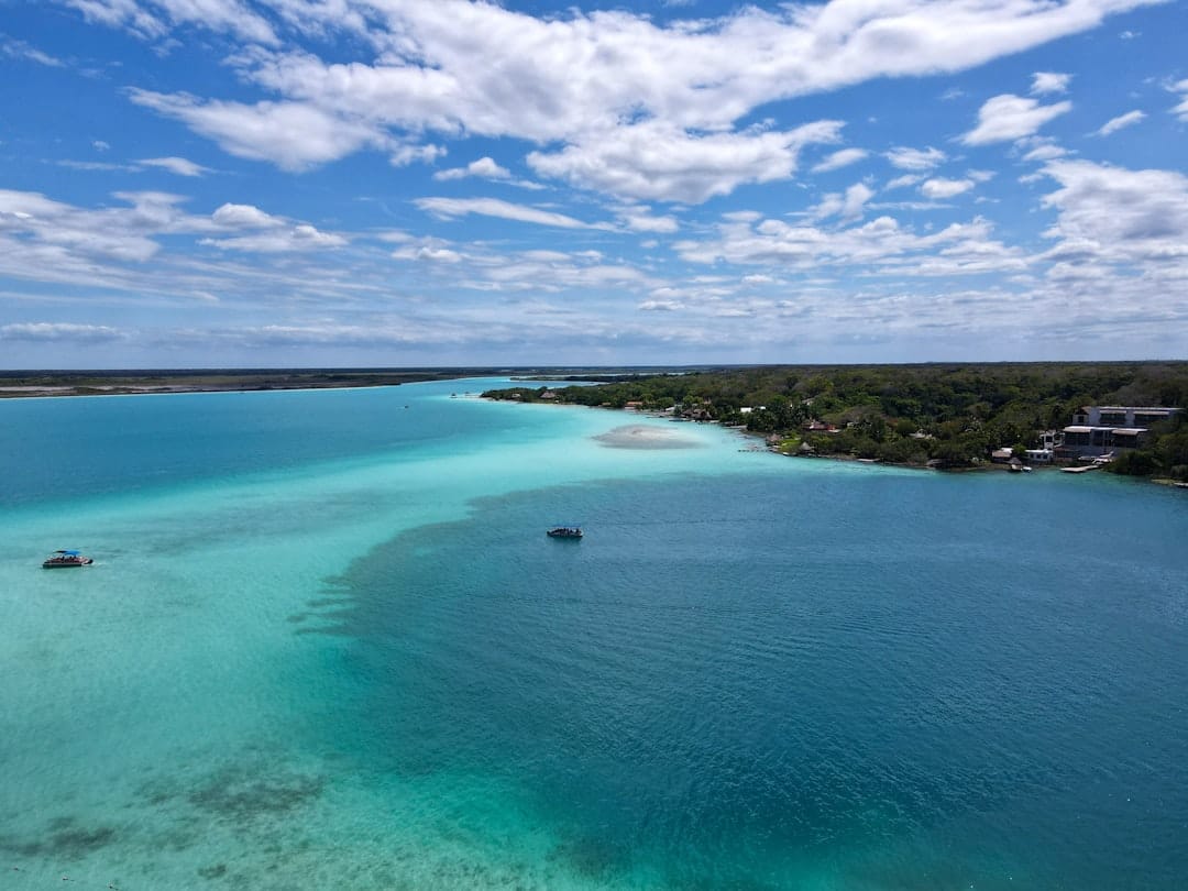 Bacalar Lagoon in Quintana Roo, Mexico from the air, one small boat on the water and a low green shore with scattered houses
