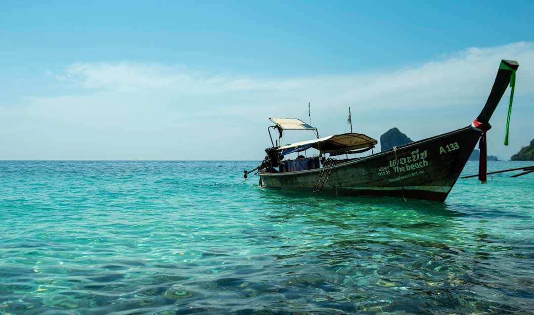 A wooden Thai longtail boat sitting in clear turquoise water off a shallow reef at Krabi