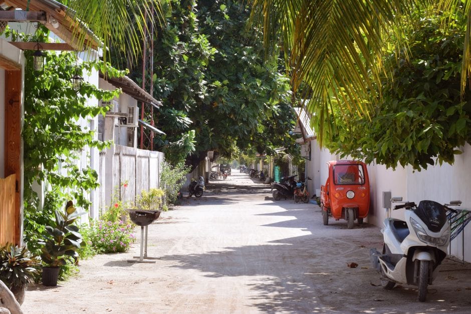 A quiet street on Thoddoo in the Maldives with motorbikes parked along a garden wall