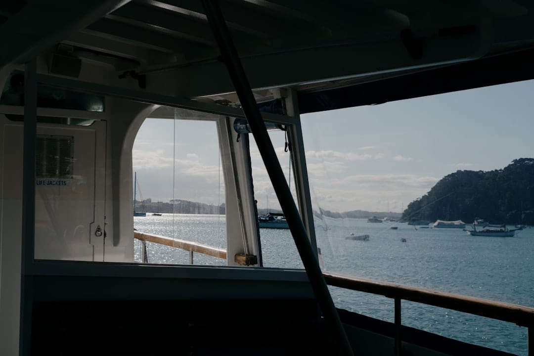 The open deck of a passenger boat at Russell in New Zealand looking out over a sheltered bay, moored boats and a wooded headland ahead