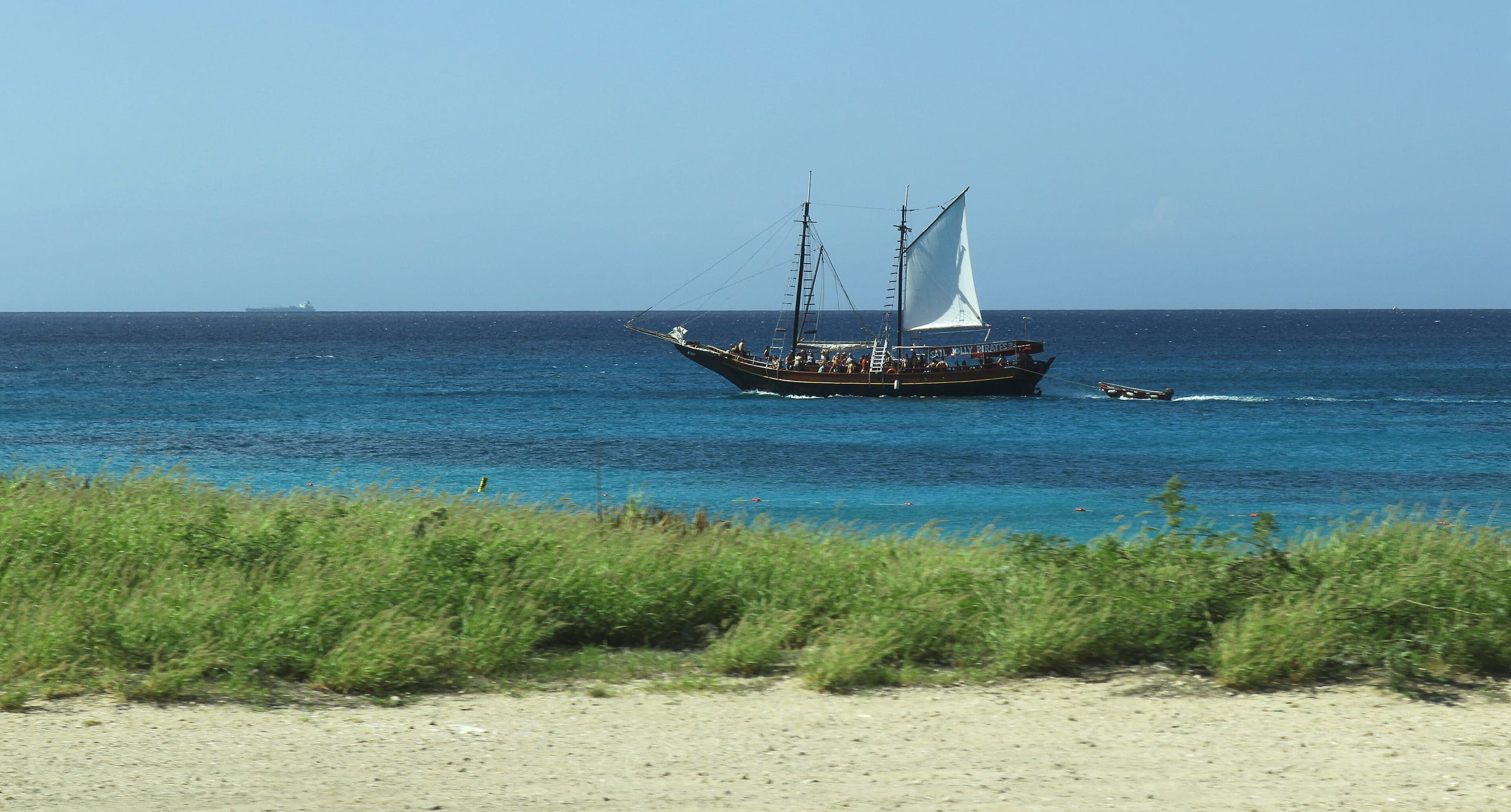 A tall-masted schooner under sail off the coast