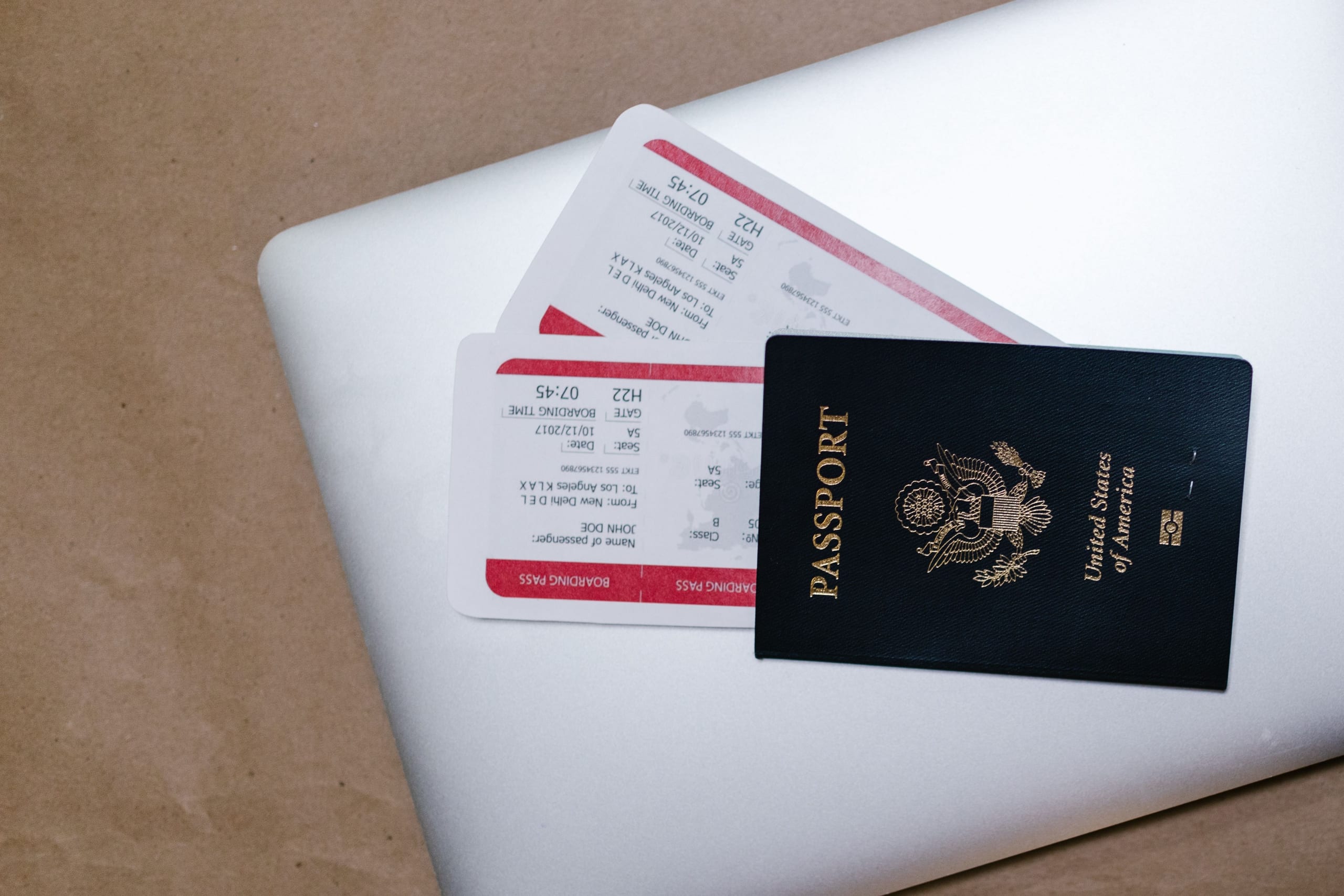A passport and two boarding passes lying on a closed laptop